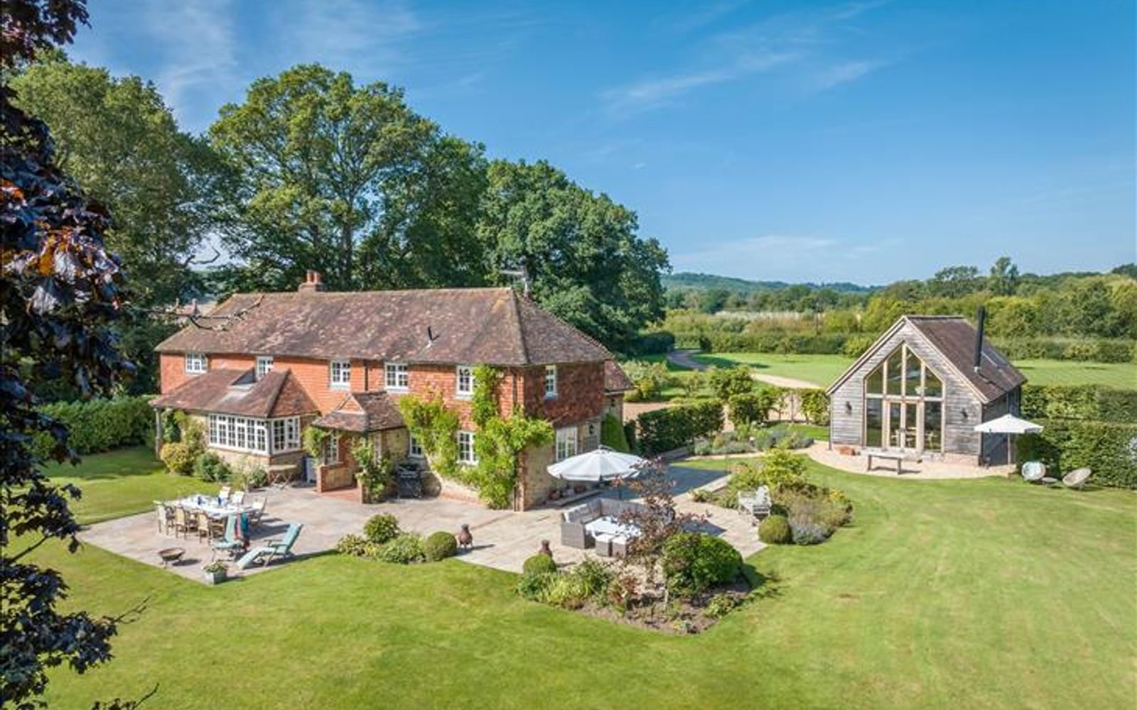 Aerial view of a West Sussex country house with converted barn and gardens
